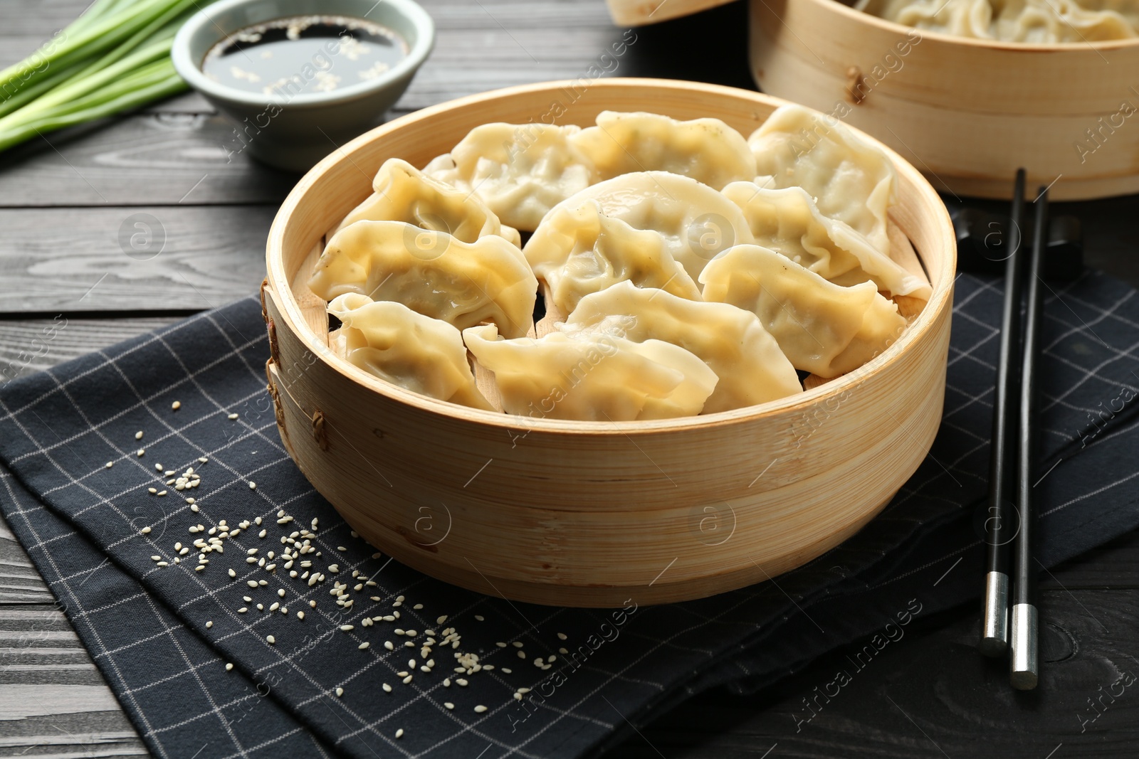 Photo of Tasty boiled gyoza (dumplings) served on black wooden table