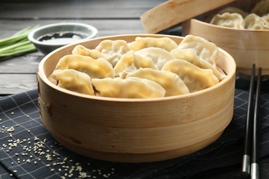 Photo of Tasty boiled gyoza (dumplings) served on black wooden table, closeup