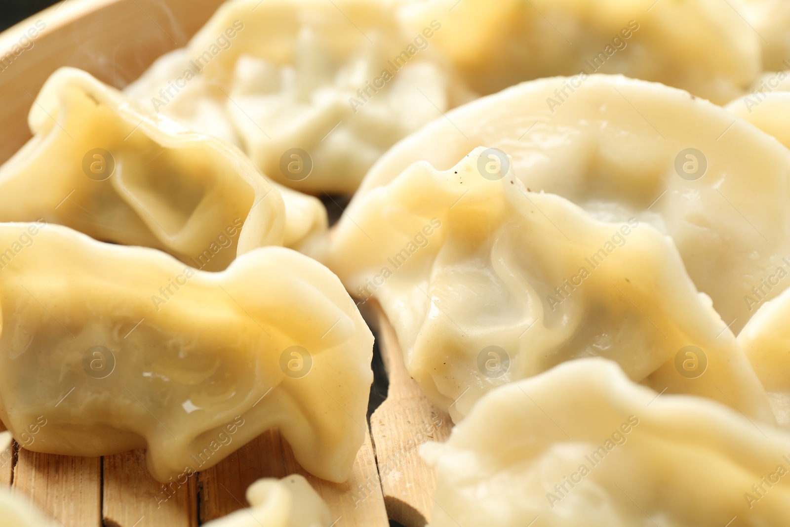 Photo of Tasty boiled gyoza (dumplings) in bamboo steamer, closeup