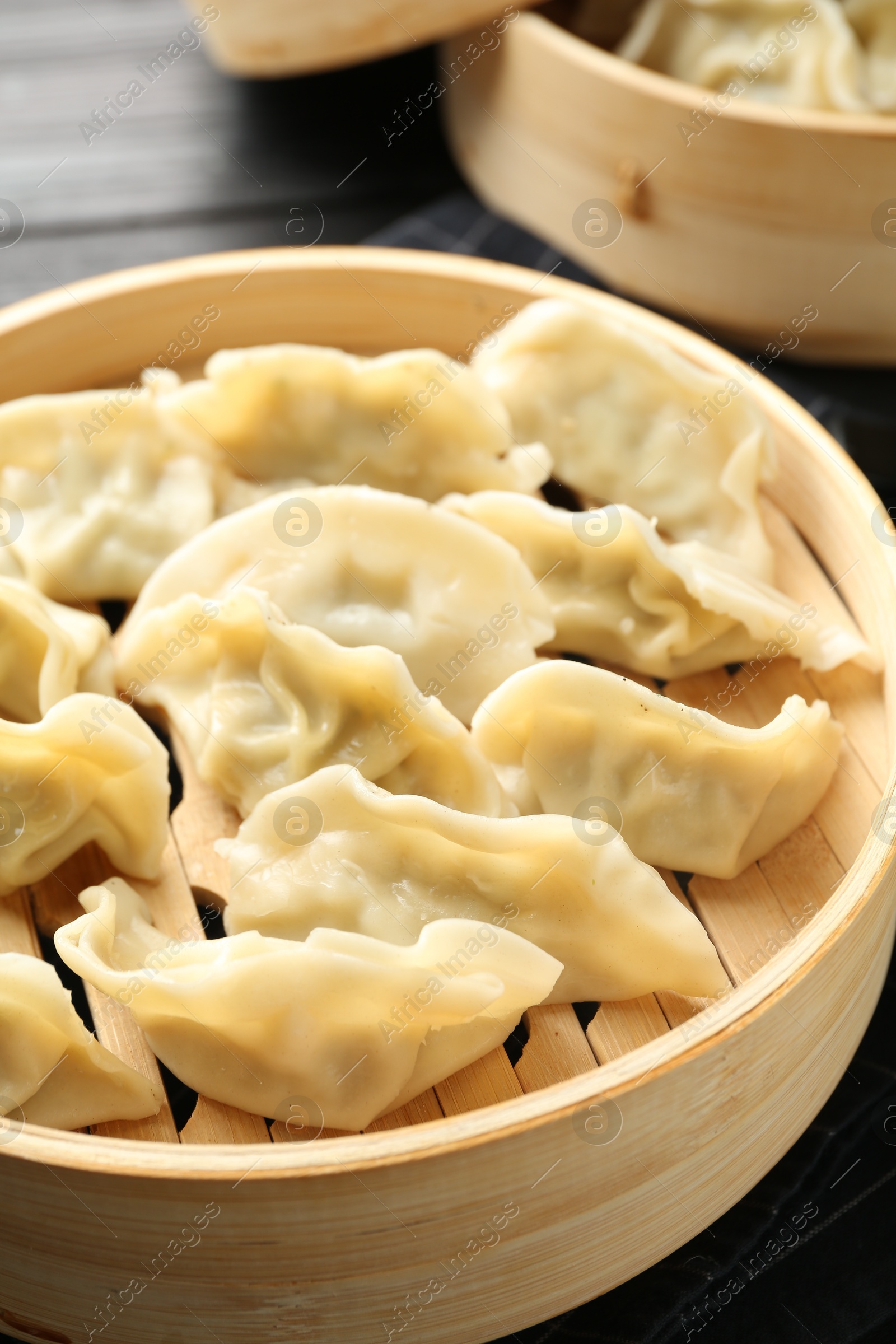 Photo of Tasty boiled gyoza (dumplings) on black table, closeup