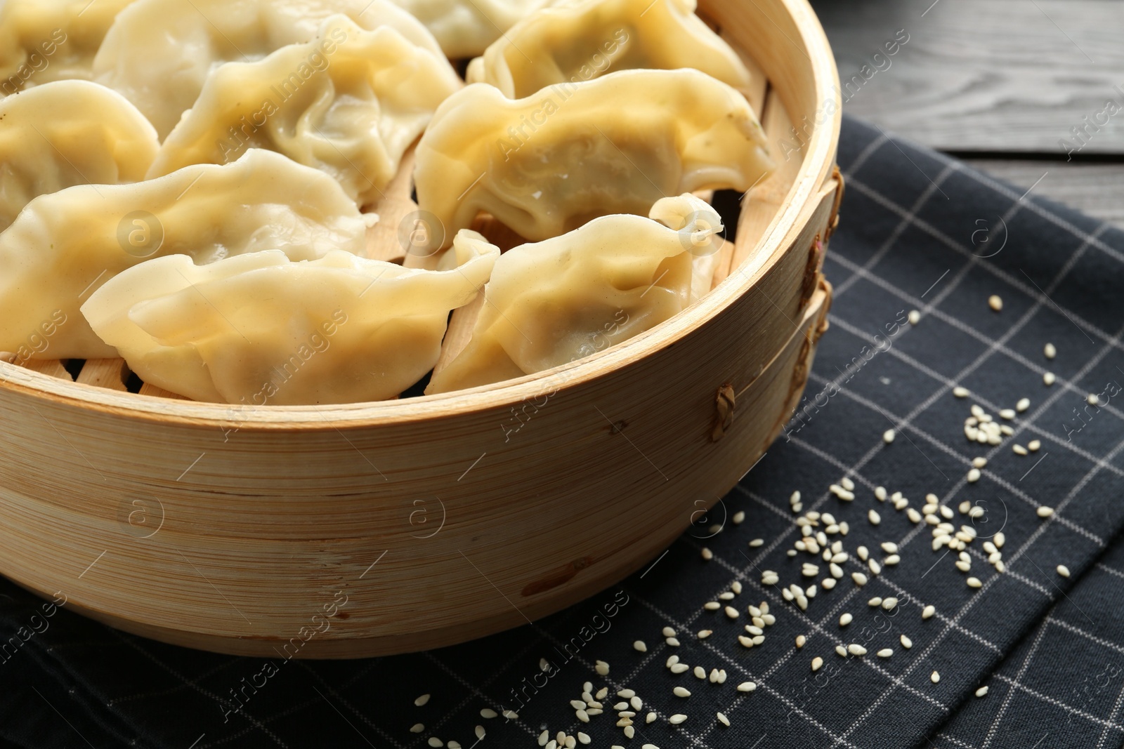 Photo of Tasty boiled gyoza (dumplings) with sesame on black table, closeup