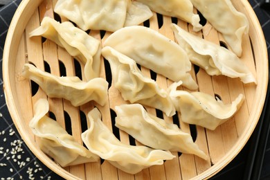 Photo of Tasty boiled gyoza (dumplings) with sesame on table, top view