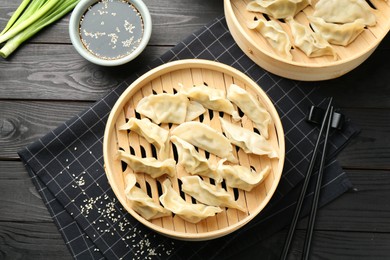 Photo of Tasty boiled gyoza (dumplings) served on black wooden table, flat lay