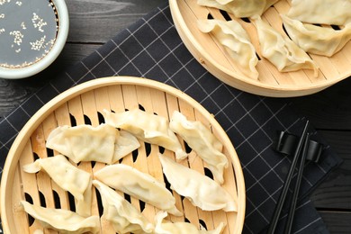 Photo of Tasty boiled gyoza (dumplings) served on black wooden table, flat lay