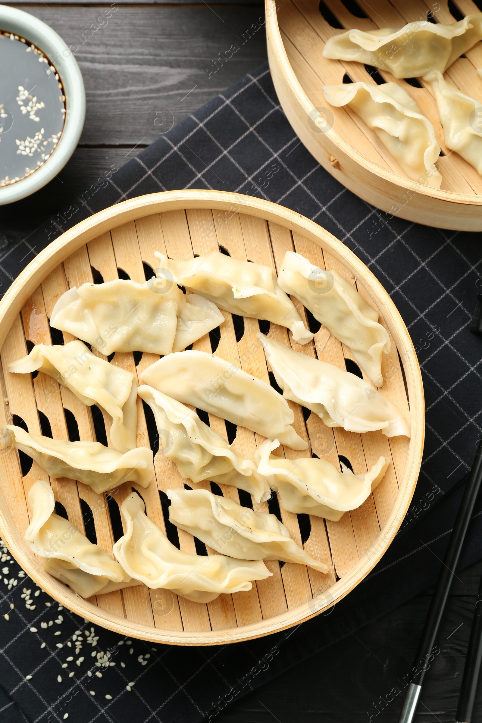 Photo of Tasty boiled gyoza (dumplings) served on black wooden table, flat lay