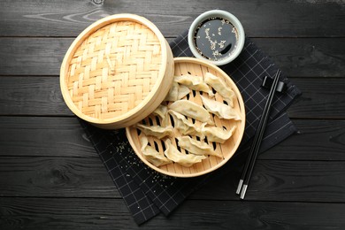 Photo of Tasty boiled gyoza (dumplings) served on black wooden table, flat lay