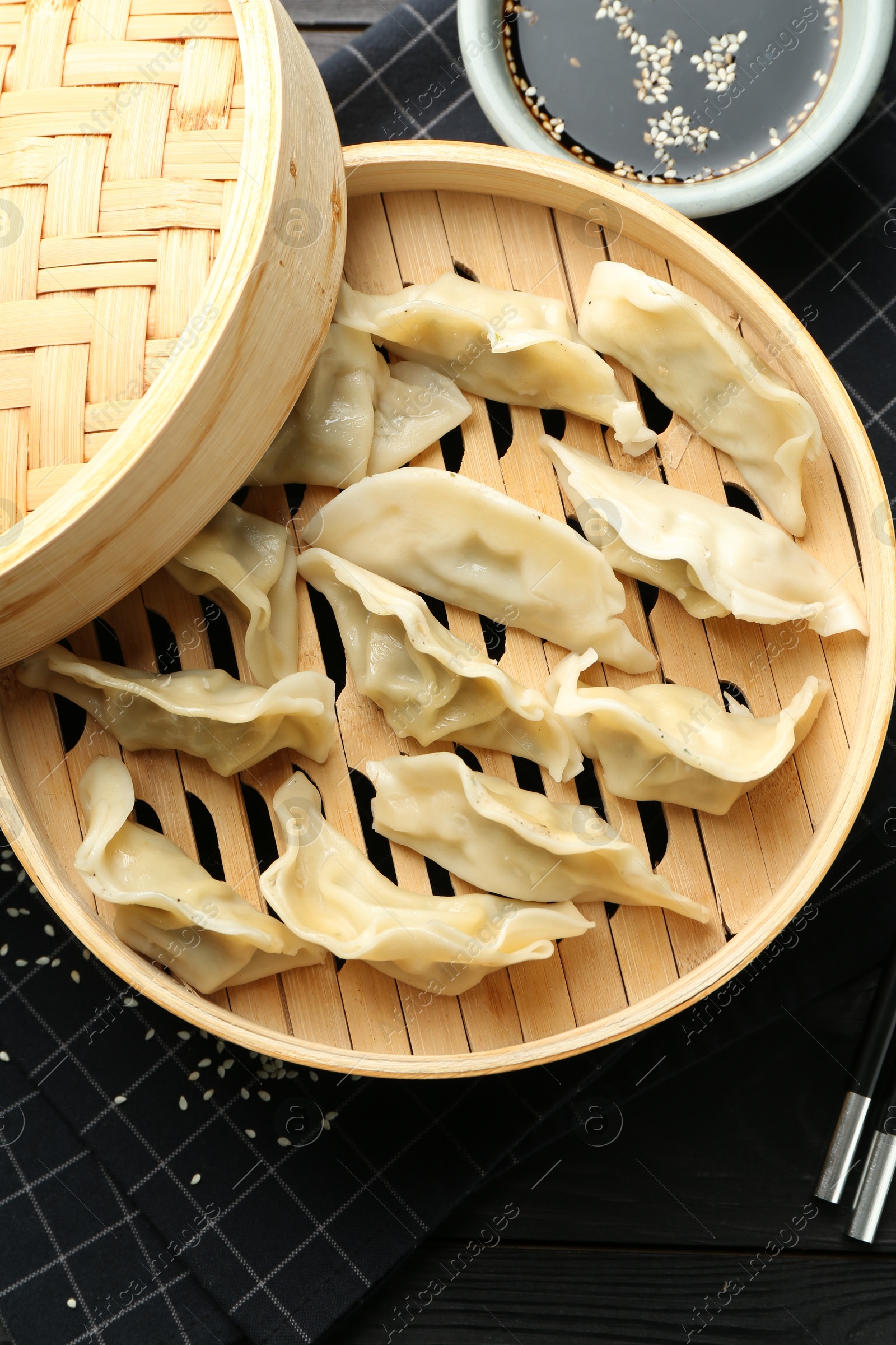 Photo of Tasty boiled gyoza (dumplings) served on black table, flat lay