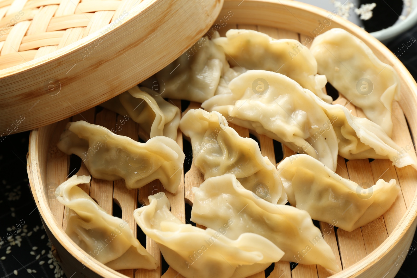 Photo of Tasty boiled gyoza (dumplings) in bamboo steamer on table, closeup