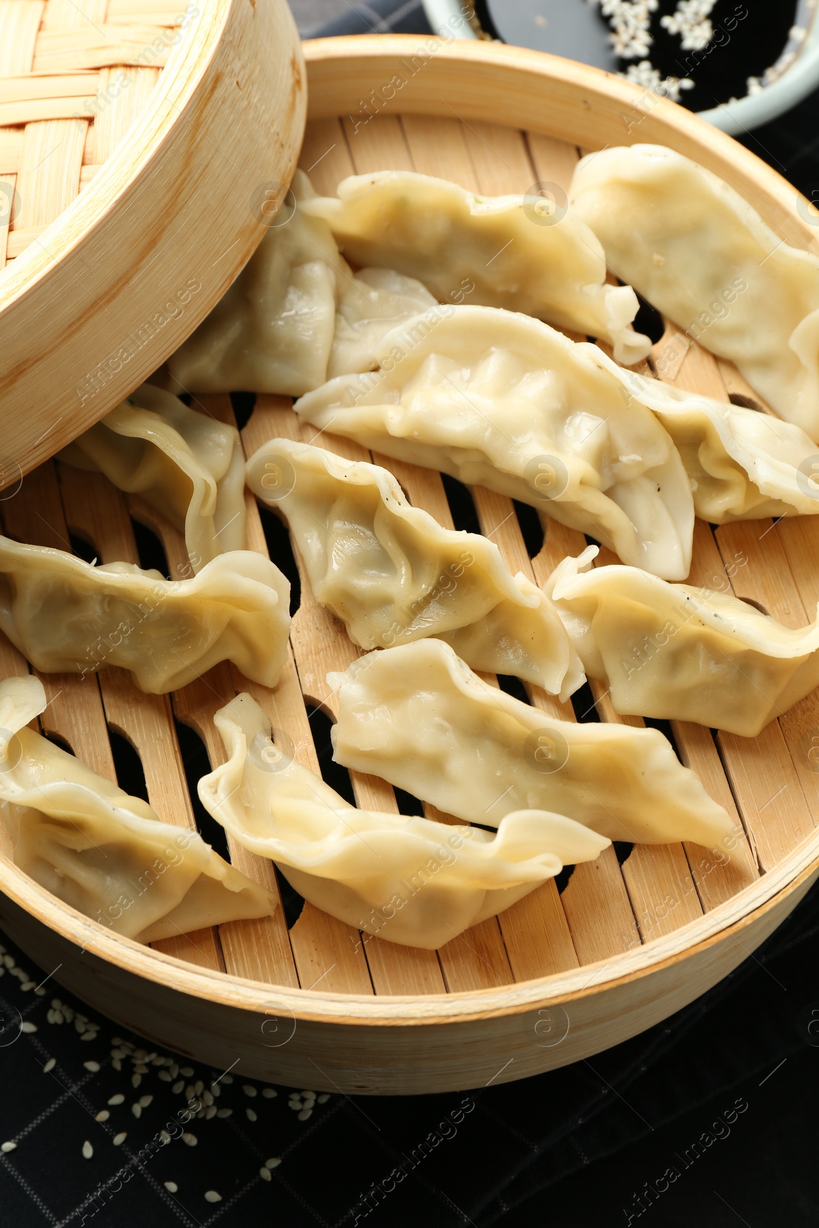 Photo of Tasty boiled gyoza (dumplings) in bamboo steamer on table, closeup