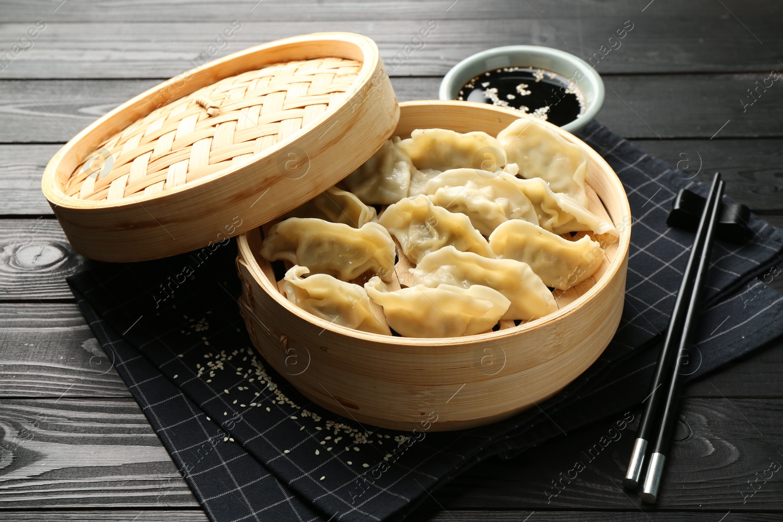 Photo of Tasty boiled gyoza (dumplings) served on black wooden table