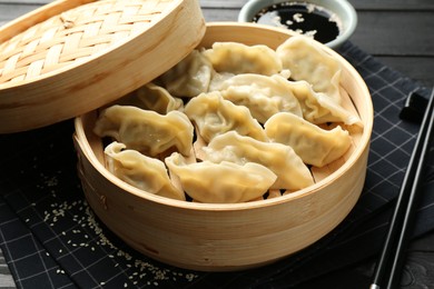 Photo of Tasty boiled gyoza (dumplings) served on black table, closeup