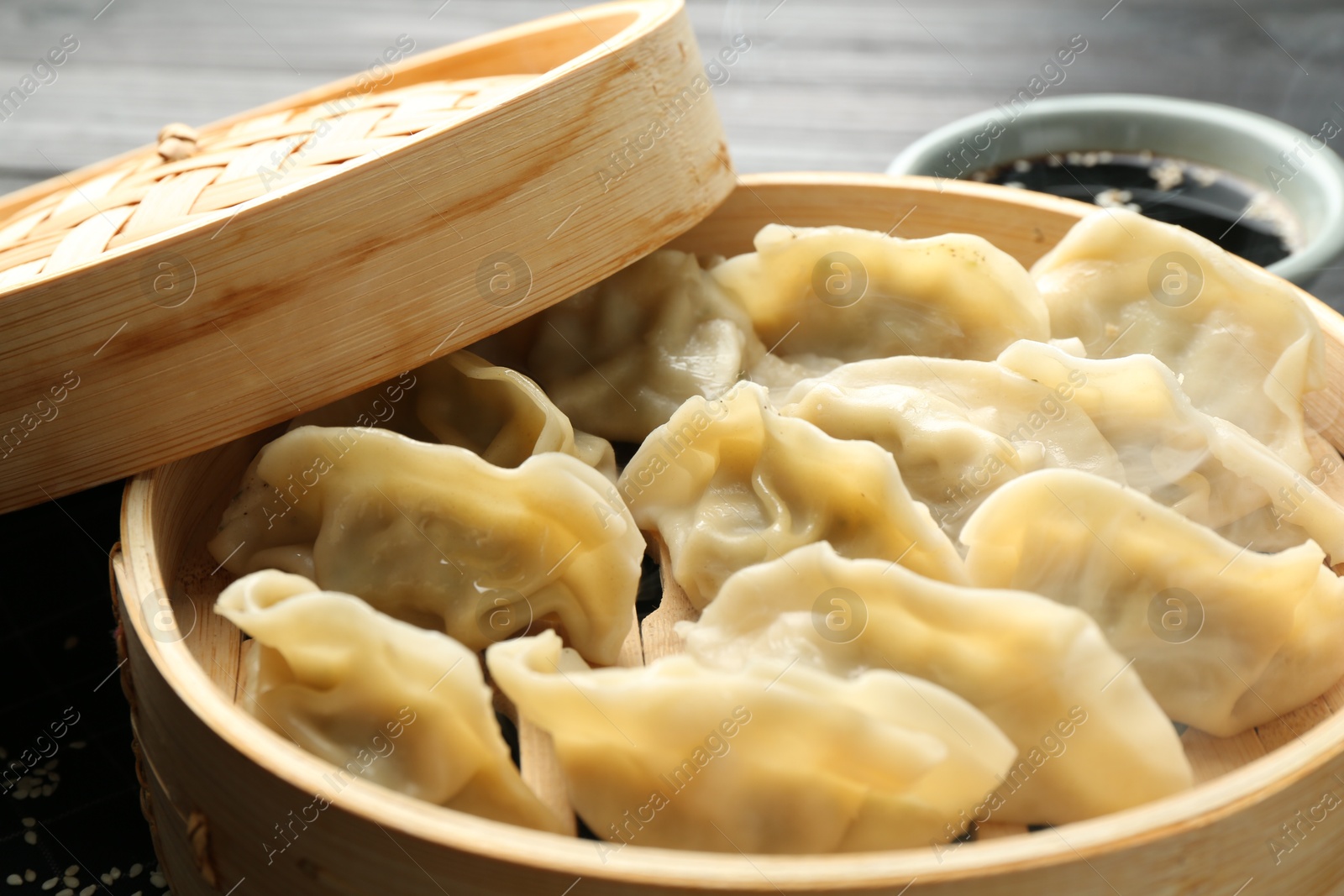 Photo of Tasty boiled gyoza (dumplings) in bamboo steamer on table, closeup