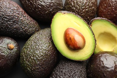 Photo of Many whole and cut ripe avocados as background, closeup