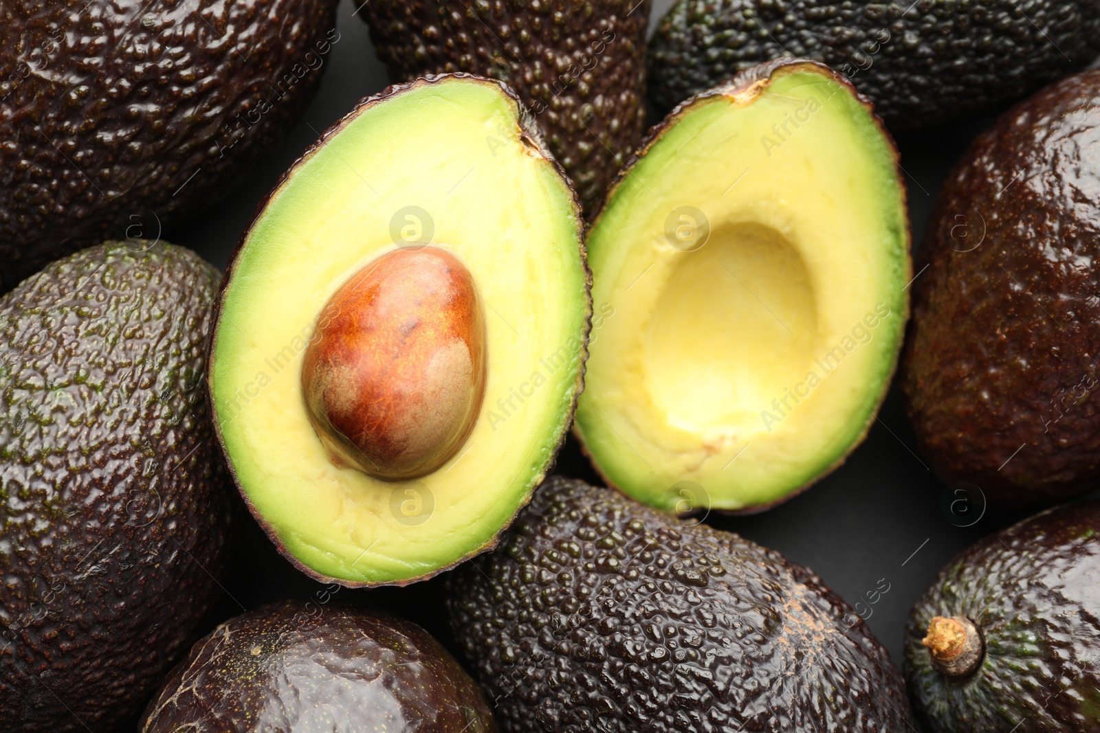 Photo of Many whole and cut ripe avocados as background, closeup