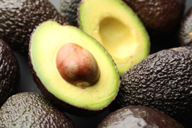 Photo of Many whole and cut ripe avocados as background, closeup