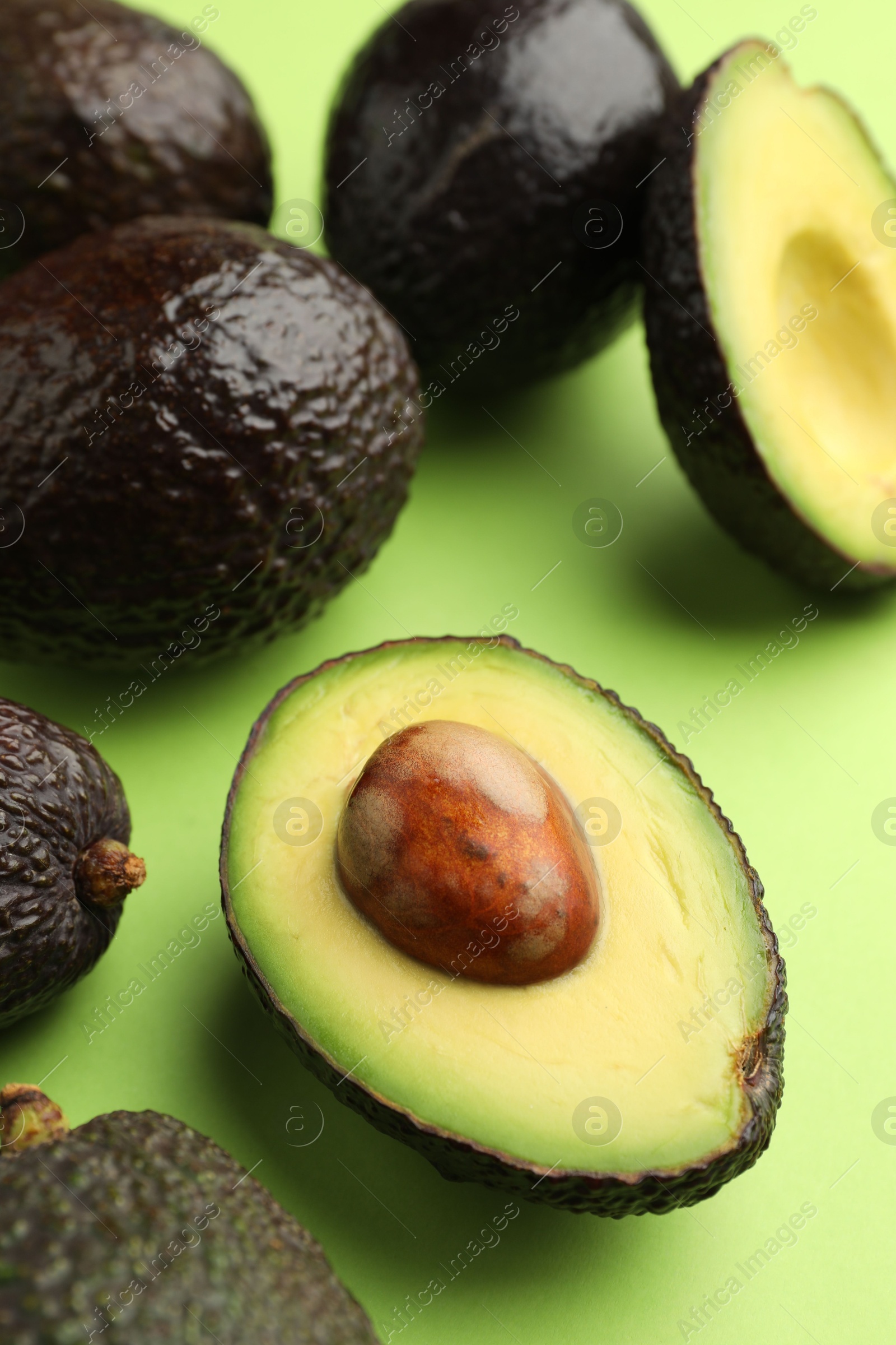 Photo of Fresh ripe avocados on light green background, closeup