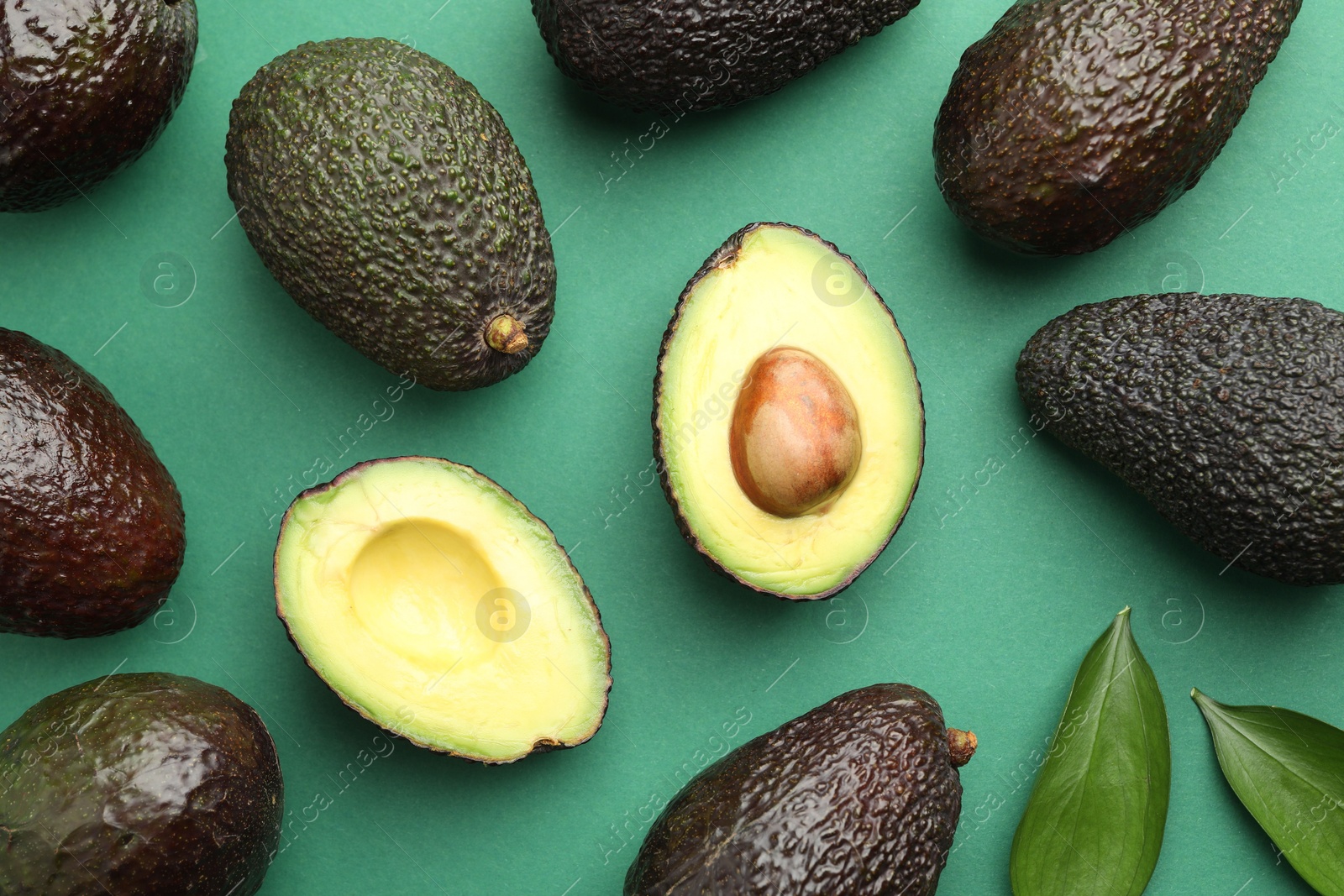 Photo of Fresh ripe avocados and leaves on teal background, flat lay