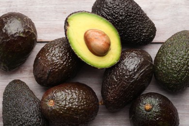 Photo of Fresh ripe avocados on light wooden table, closeup