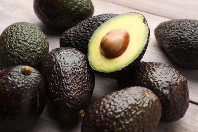 Photo of Fresh ripe avocados on light wooden table, closeup