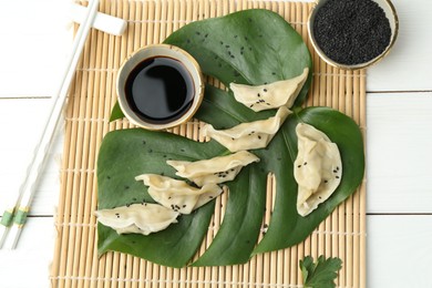 Photo of Tasty boiled gyoza (dumplings) served on white wooden table, flat lay