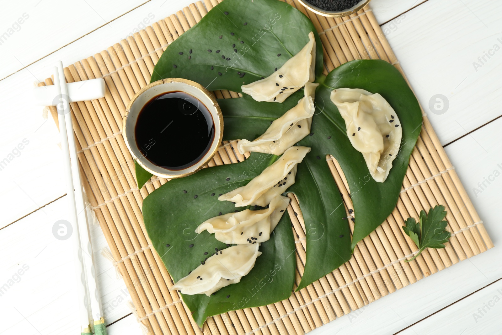 Photo of Tasty boiled gyoza (dumplings) served on white wooden table, flat lay