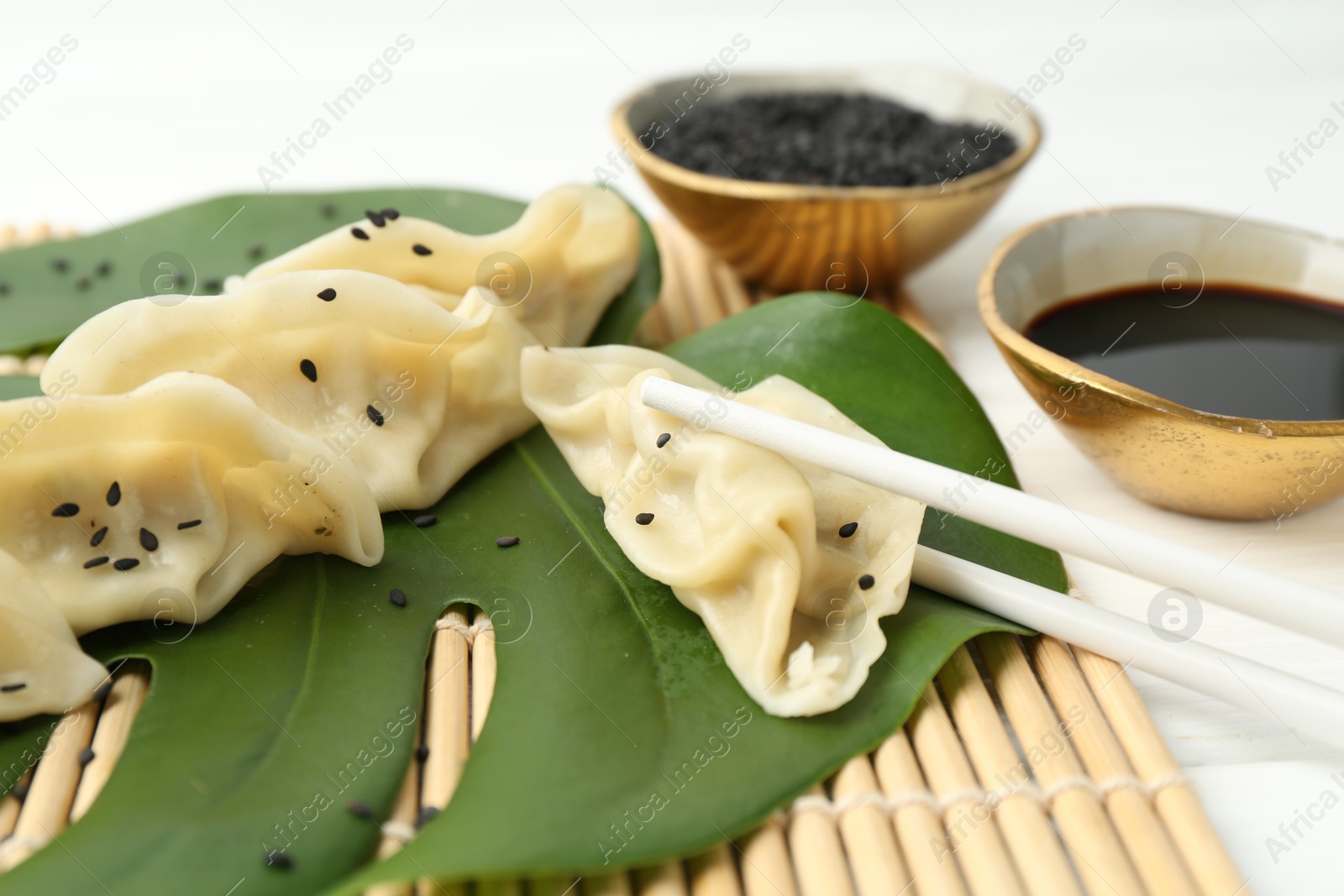 Photo of Tasty boiled gyoza (dumplings) served on white wooden table, closeup