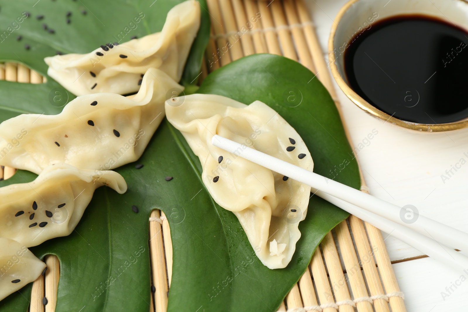 Photo of Tasty boiled gyoza (dumplings) served on white wooden table, closeup