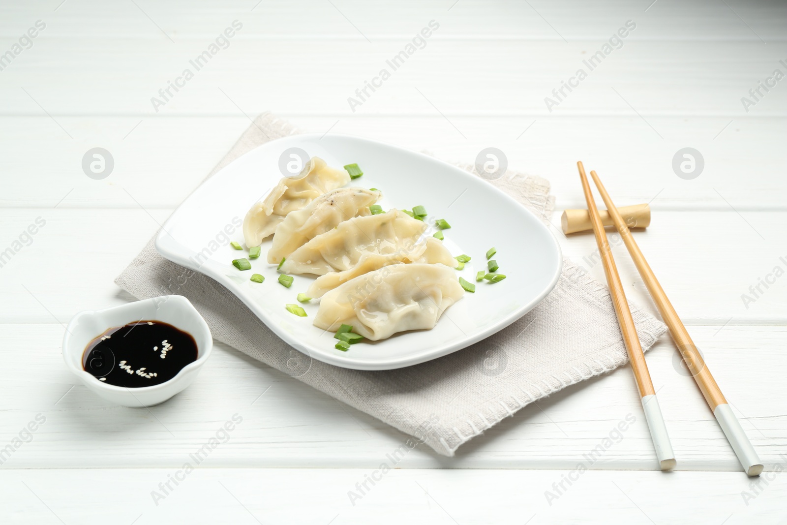 Photo of Tasty boiled gyoza (dumplings) served on white wooden table