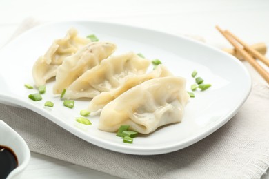 Photo of Tasty boiled gyoza (dumplings) with green onion served on white table, closeup