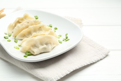 Photo of Tasty boiled gyoza (dumplings) with green onion on white wooden table, closeup. Space for text