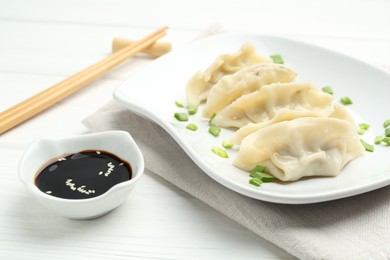 Photo of Tasty boiled gyoza (dumplings) served on white wooden table, closeup