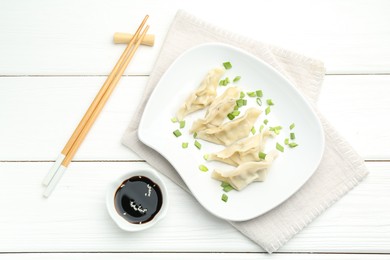 Photo of Tasty boiled gyoza (dumplings) served on white wooden table, flat lay