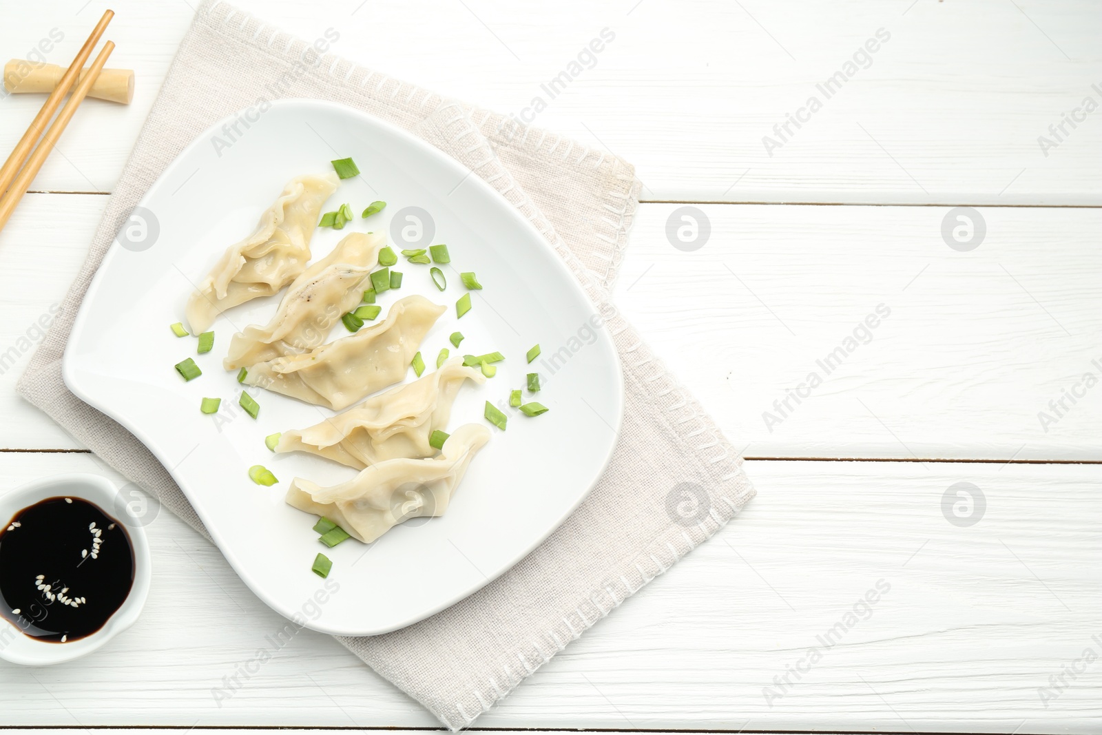 Photo of Tasty boiled gyoza (dumplings) served on white wooden table, flat lay. Space for text