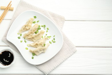 Photo of Tasty boiled gyoza (dumplings) served on white wooden table, flat lay. Space for text