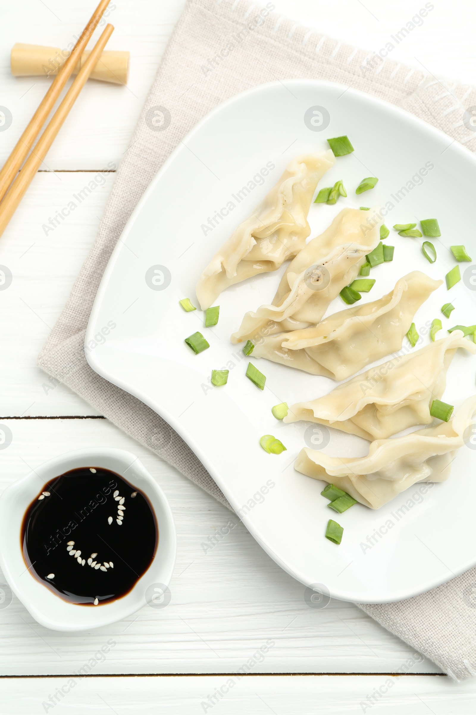 Photo of Tasty boiled gyoza (dumplings) served on white wooden table, flat lay