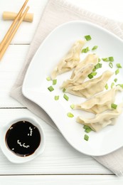 Photo of Tasty boiled gyoza (dumplings) served on white wooden table, flat lay