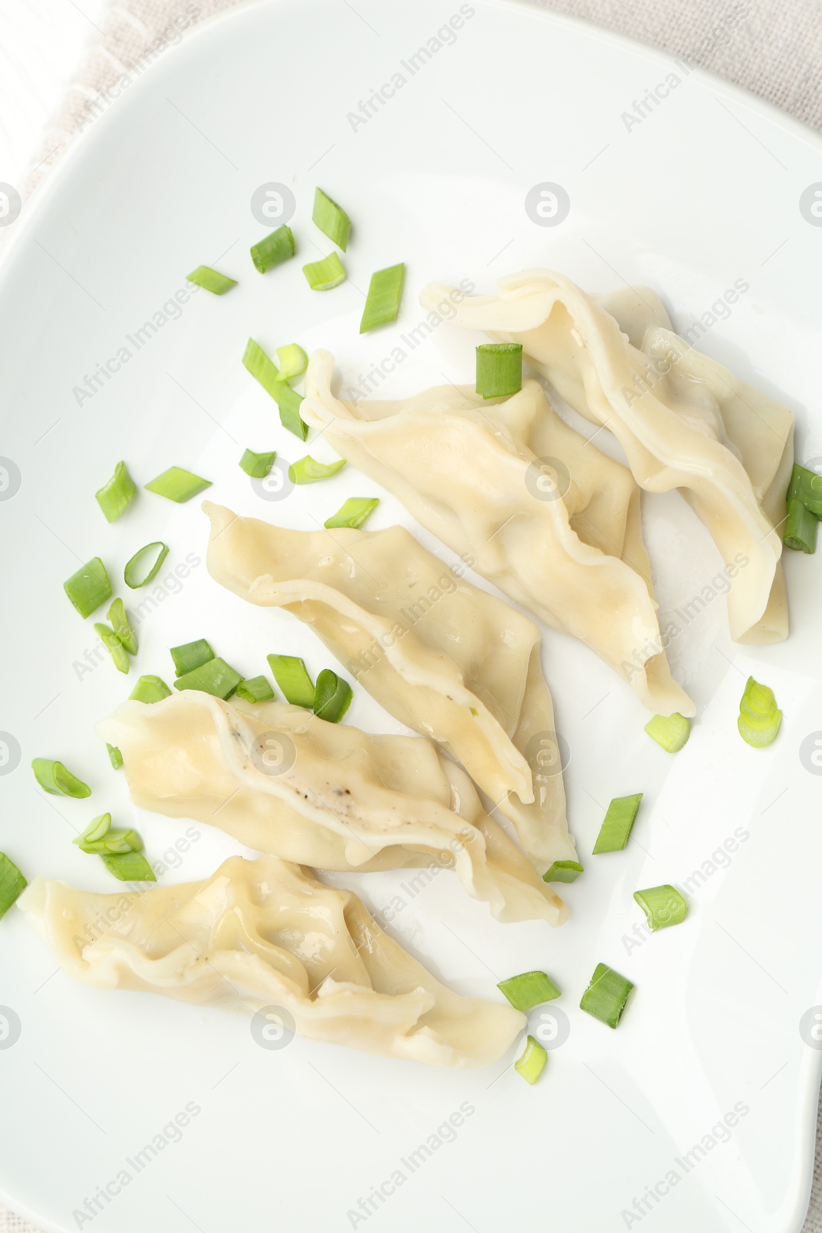 Photo of Tasty boiled gyoza (dumplings) with green onion on white table, top view