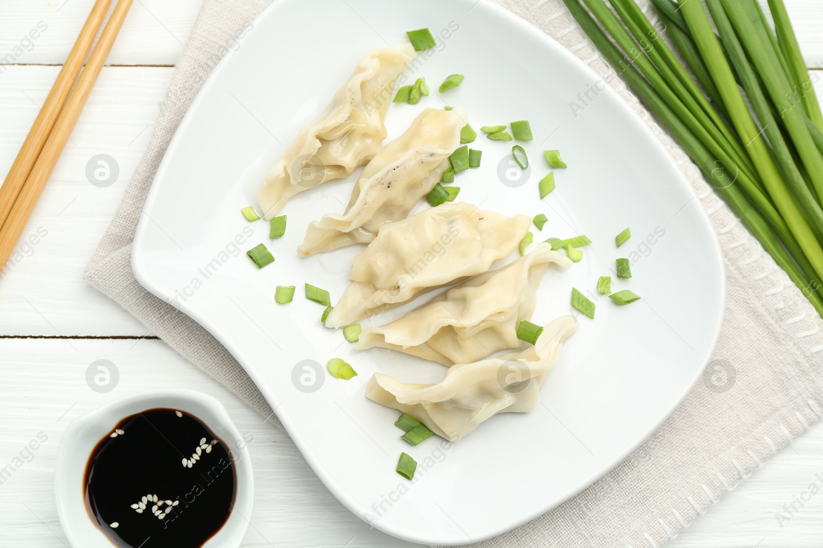 Photo of Tasty boiled gyoza (dumplings) served on white wooden table, flat lay