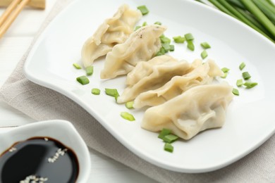 Photo of Tasty boiled gyoza (dumplings) served on white wooden table, closeup