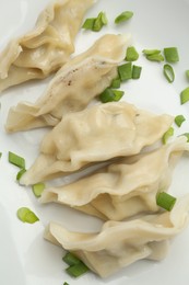 Photo of Tasty boiled gyoza (dumplings) with green onion on plate, top view