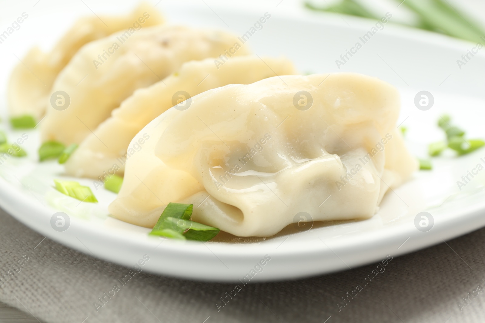 Photo of Tasty boiled gyoza (dumplings) with green onion on table, closeup