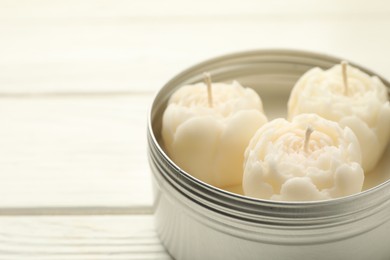 Photo of Beautiful flower-shaped candles in jar on white wooden table, closeup. Space for text