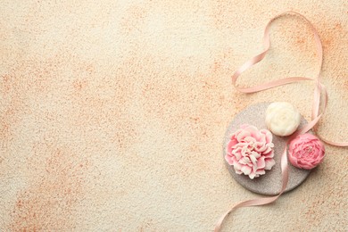 Photo of Beautiful flower-shaped candles and ribbon on beige textured background, top view. Space for text