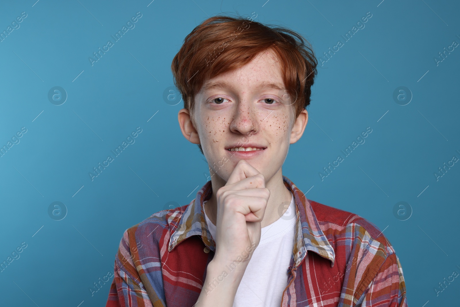 Photo of Smiling teenage boy with freckles on light blue background