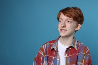 Photo of Smiling teenage boy with freckles on light blue background. Space for text