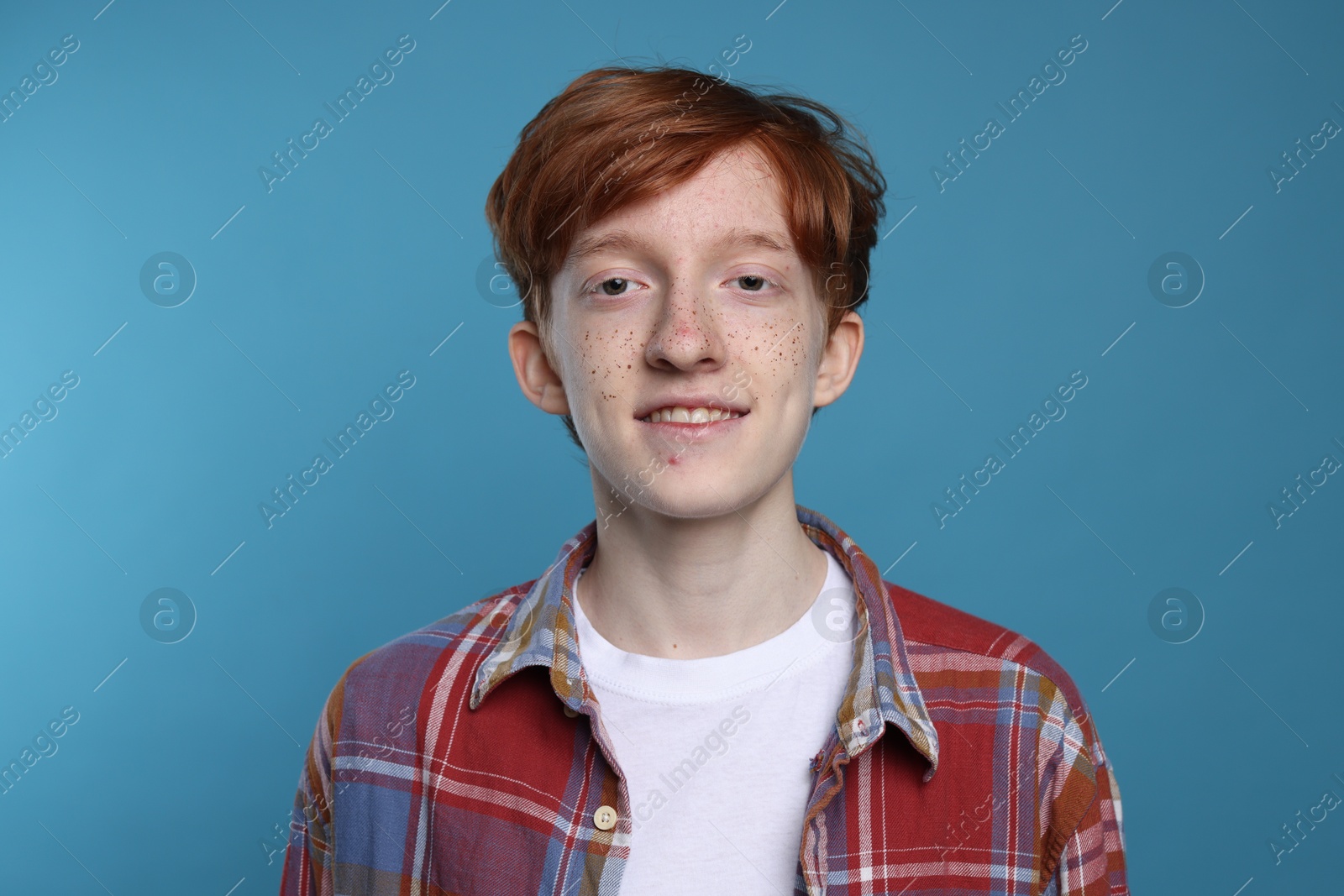 Photo of Smiling teenage boy with freckles on light blue background