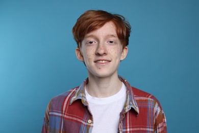 Photo of Smiling teenage boy with freckles on light blue background