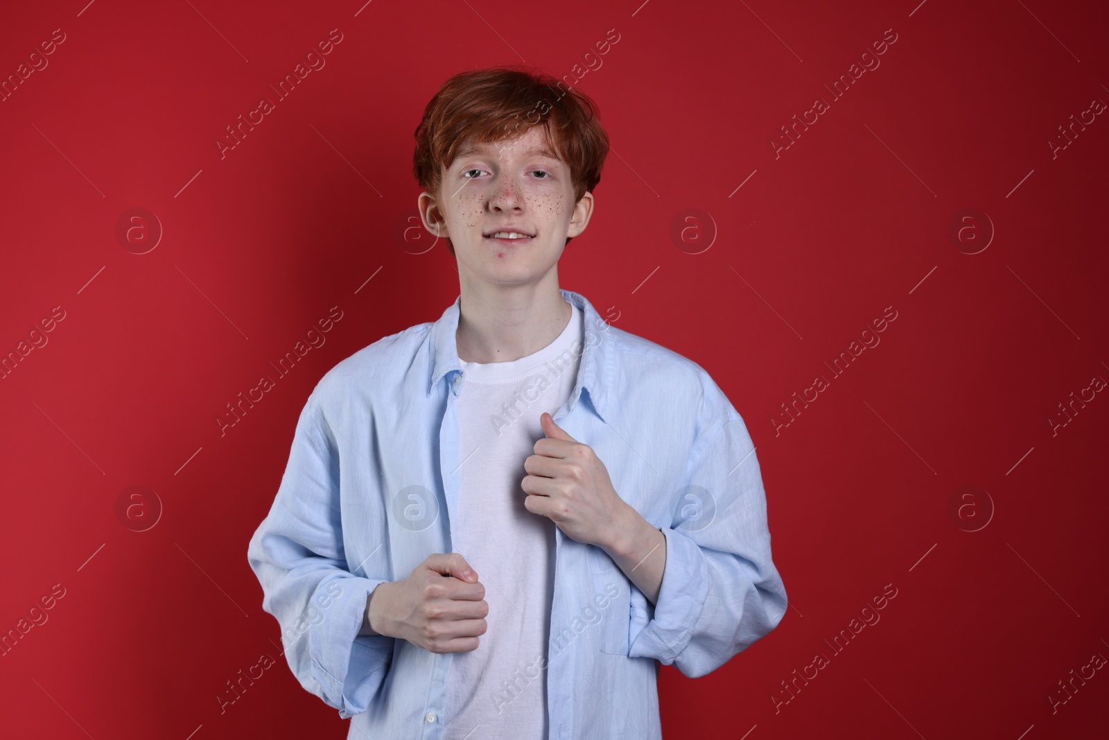 Photo of Smiling teenage boy with freckles on red background