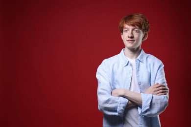 Photo of Teenage boy with freckles on dark red background. Space for text