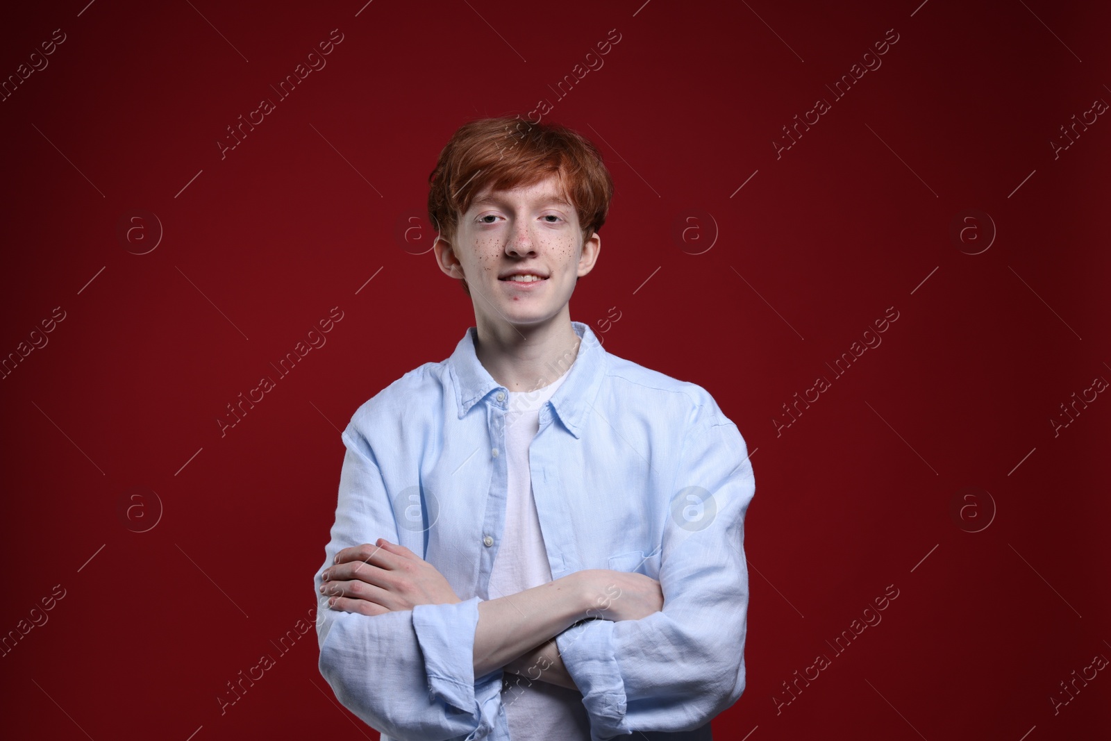 Photo of Smiling teenage boy with freckles on dark red background